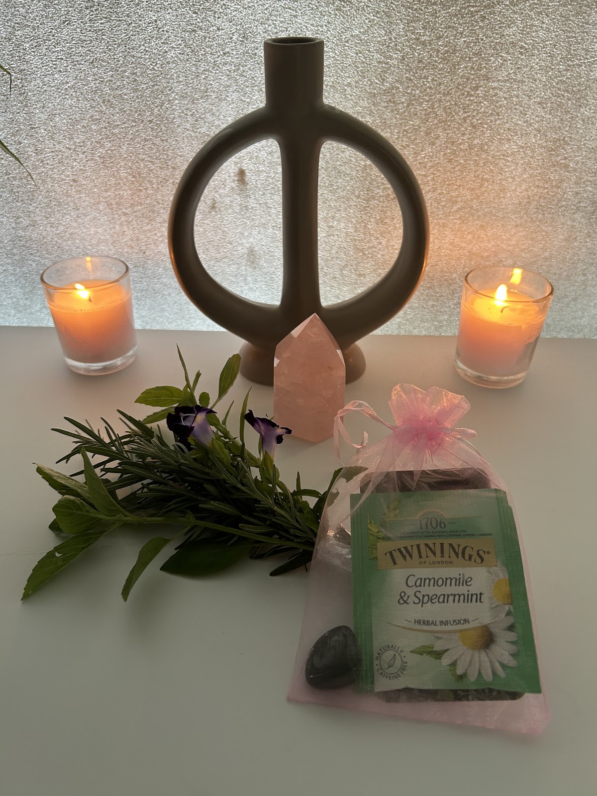 Candles, a rose quartz crystal, fresh rosemary and a gift bag with herbal tea, ready for a client